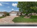 Inviting single-story home featuring a manicured lawn, brick driveway, and mature shade tree at 1748 Sw 157Th Place Rd, Ocala, FL 34473