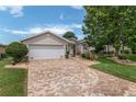 Inviting single-story home featuring a manicured lawn, brick driveway, and well-maintained landscaping at 1748 Sw 157Th Place Rd, Ocala, FL 34473