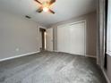 Spacious bedroom with soft gray carpet, a ceiling fan, and a double door closet for ample storage at 21 Pecan Course Cir, Ocala, FL 34472