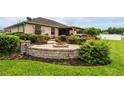 Landscaped backyard featuring a circular brick patio with built-in fire pit and lush green lawn at 4015 Se 22Nd St, Ocala, FL 34471