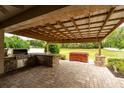 Covered patio with outdoor kitchen, granite countertop, grill, and adjacent hot tub at 4015 Se 22Nd St, Ocala, FL 34471