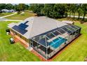 Aerial view of home showcasing a large screened-in pool enclosure and solar panels at 5815 Ne 70Th St, Silver Springs, FL 34488