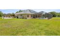 A green backyard featuring a screened-in lanai and private pool with a fence for privacy at 6573 S Magnolia Ave, Ocala, FL 34471