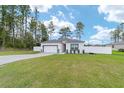 Landscaped lawn featuring a driveway leading to a white single-story home with an attached garage at 7479 Sw 130Th Ln, Ocala, FL 34473