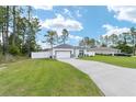 Landscaped lawn featuring a driveway leading to a white single-story home with an attached garage at 7479 Sw 130Th Ln, Ocala, FL 34473