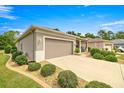 Home's exterior featuring a long driveway leading to an attached two-car garage and manicured landscaping at 7917 Sw 85Th Loop, Ocala, FL 34476