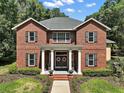 Charming brick home with a welcoming entrance, showcasing classic columns and decorative wreaths on double doors at 9175 Se 7Th Avenue Rd, Ocala, FL 34480