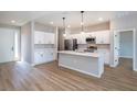 Bright open-concept kitchen with white cabinets, stainless steel appliances, island, and wood-look flooring at 10207 Sw 41St W Ter, Ocala, FL 34476