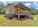 Attractive home featuring a covered porch with hanging plants, and a beautifully landscaped yard at 12080 Se Sunset Harbor Rd, Weirsdale, FL 32195