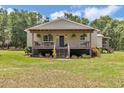 Charming home featuring a welcoming porch with hanging plants and a manicured lawn at 12080 Se Sunset Harbor Rd, Weirsdale, FL 32195