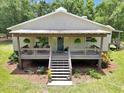 Inviting home with a cozy front porch, hanging ferns, and well-maintained landscaping at 12080 Se Sunset Harbor Rd, Weirsdale, FL 32195