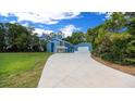 Two-story blue home with a long driveway and detached garage surrounded by lush trees and blue sky at 12690 Ne Highway 315, Fort Mc Coy, FL 32134
