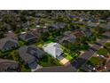 An aerial view of a home with a screened-in lanai, nestled in a quiet neighborhood with mature trees at 1308 La Estrellita Way, The Villages, FL 32162