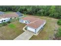 Aerial view showcasing the single-story home with a neutral gray paint scheme, brown roof, long driveway, and two-car garage at 14550 Sw 61St Ct, Ocala, FL 34473