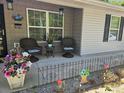 Cozy front porch features comfortable chairs, decorative flower arrangements, and a welcoming entrance to the home at 19370 Saint Benedict Dr, Dunnellon, FL 34432