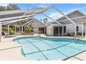 Inviting screened-in pool area featuring a sparkling pool, lounge chairs, and a spacious deck at 19942 Sw 96Th Pl, Dunnellon, FL 34432