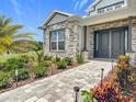 Stunning home entrance featuring a paved walkway, stone accents, and beautiful landscaping at 4370 County Road 121D, Wildwood, FL 34785