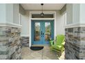 Charming entrance with a decorative double door, stone accents, and a welcoming green chair at 8772 Se 130Th Loop, Summerfield, FL 34491