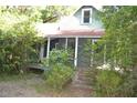 Quaint two-story home with a covered porch, surrounded by lush greenery and mature trees at 1050 E Highway 329, Citra, FL 32113