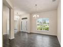 Bright living room features elegant chandeliers, wood-look tile flooring, and a large window with a pleasant view at 10910 Sw 41St Ave, Ocala, FL 34476
