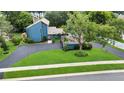 Aerial view of a modern blue home featuring a well-manicured lawn, driveway, and mature landscaping at 2922 Cocovia Way, Leesburg, FL 34748
