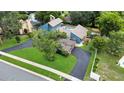 Aerial view of a modern blue home with pool, large driveway, mature trees and lush landscaping at 2922 Cocovia Way, Leesburg, FL 34748