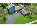 Aerial view of a modern blue home with a large driveway, a pool and lush landscaping at 2922 Cocovia Way, Leesburg, FL 34748