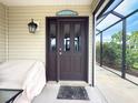 Inviting front door with sidelights, and a covered porch area with seating and screened windows at 3021 Beard Rd, The Villages, FL 32163