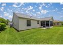 Backyard view showing the home's exterior with screen enclosed lanai and well-maintained lawn at 3024 Burbank Ln, The Villages, FL 32162