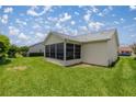 Backyard view featuring a screened-in lanai and lush lawn at 3024 Burbank Ln, The Villages, FL 32162