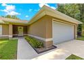 Side view of home featuring attached garage, covered entry way, and manicured flower beds at 3445 Se 139Th Ln, Summerfield, FL 34491