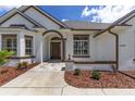 Inviting front entrance with a dark door, elegant stonework, lush landscaping, and a well-manicured lawn at 5092 Ne 81St Blvd, Wildwood, FL 34785