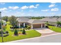 Well-manicured single-story home featuring a three-car garage, lush landscaping, and a pristine front lawn at 6683 Sw 97Th Terrace Rd, Ocala, FL 34481