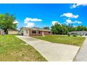 Brick home featuring a long driveway, and a spacious front yard with lush green grass at 6989 Se 52Nd Pl, Ocala, FL 34472