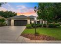 Charming single Gathering home with a well maintained lawn, mature tree, and a two-car garage at dusk at 8961 Se 130Th Loop, Summerfield, FL 34491