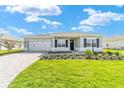 Charming one-story home with a lush green lawn, brick driveway, attached garage, and neatly landscaped flower beds at 9865 Sw 105Th Ct, Ocala, FL 34481