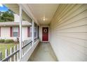 Charming covered front porch with a decorative wreath on a red front door, offering curb appeal and a welcoming entrance at 12 Hemlock Radial Pass, Ocala, FL 34472