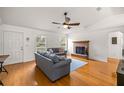 Spacious living room with hardwood floors, featuring a brick fireplace, and a ceiling fan for added comfort at 12 Hemlock Radial Pass, Ocala, FL 34472