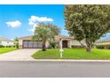 Charming home featuring a well-manicured lawn and a classic exterior design with mature trees at 13715 Se 88Th Ct, Summerfield, FL 34491