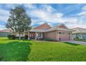 Well-maintained front lawn with neatly trimmed landscaping, a brick walkway and chairs on the front porch at 145 Harbor Way, Auburndale, FL 33823