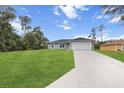 Beautiful single-story home with a large driveway, lush green lawn and mature trees at 17277 Sw 44Th Cir, Ocala, FL 34473