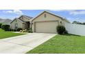 Neutral home with a wide driveway, two-car garage, manicured lawn, and white picket fence at 186 Nw 44Th St, Ocala, FL 34475