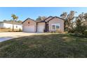 Charming home featuring a three-car garage, neutral siding, landscaped front yard and blue sky at 19551 Sw 77Th Loop, Dunnellon, FL 34432