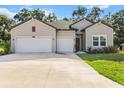 Beautiful home featuring a spacious driveway, light gray siding, double garage, and manicured lawn at 19551 Sw 77Th Loop, Dunnellon, FL 34432