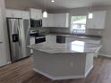 Modern kitchen featuring white cabinets, stainless steel appliances, gray countertops, and a center island at 23 Oak Pass Loop, Ocala, FL 34472