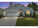 Well-lit home exterior featuring a manicured lawn and two car garage at 32 Hickory Course Loop, Ocala, FL 34472