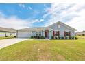 Charming single-story home with a well-manicured lawn, attached garage, and inviting red door at 3418 Sw 155Th Pl, Ocala, FL 34473