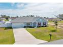 Charming single-story home with a well-manicured lawn, attached garage, and inviting red door at 3418 Sw 155Th Pl, Ocala, FL 34473
