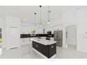 Modern kitchen with white cabinets, black countertops, stainless steel appliances, and a center island at 8456 Se 164Th Pl, Summerfield, FL 34491