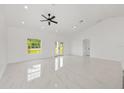 Spacious living room featuring white tile floors, neutral walls, a modern ceiling fan, and ample natural light at 8456 Se 164Th Pl, Summerfield, FL 34491